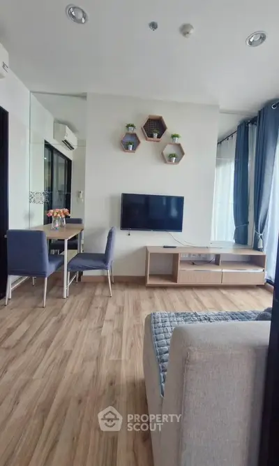 Modern living room with stylish decor, wall-mounted TV, and cozy seating area in a bright apartment.