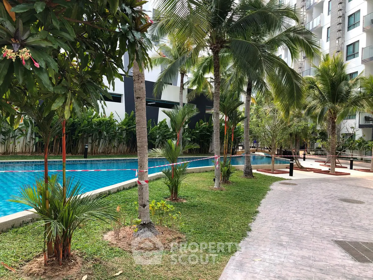 Luxurious residential pool area with lush greenery and palm trees, perfect for relaxation.
