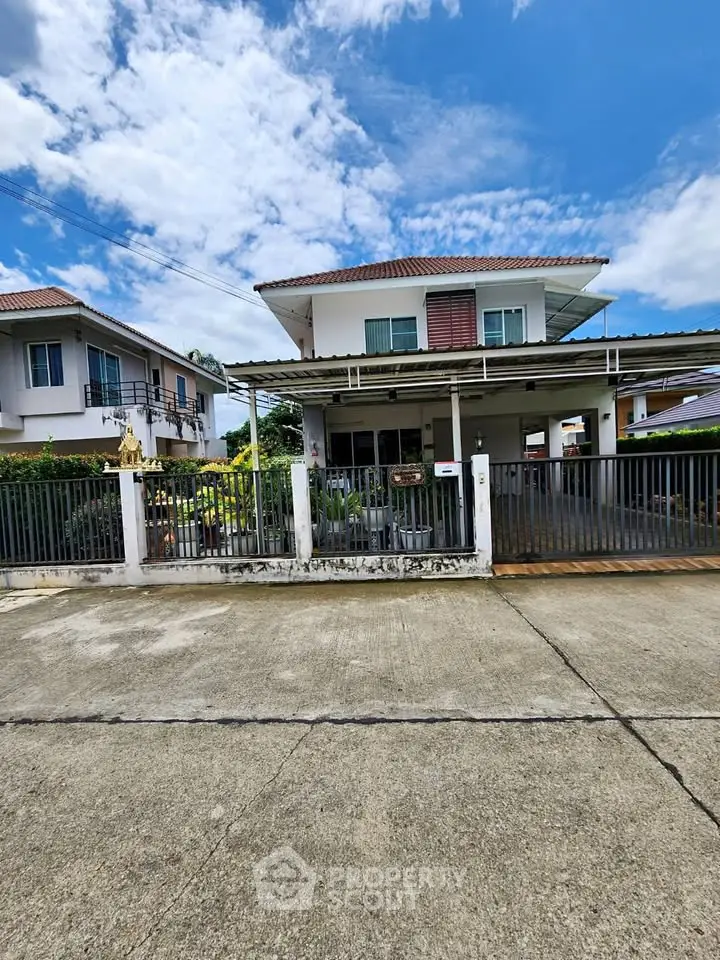 Charming two-story house with gated entrance and spacious driveway in a serene neighborhood.