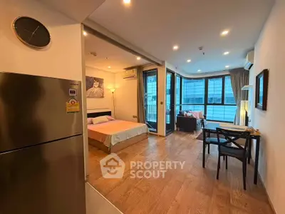 Modern open-plan studio with wooden flooring and large windows offering city views.