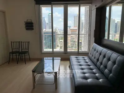 Modern living room with city view, featuring sleek black sofa and glass coffee table.
