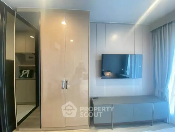Modern living room with sleek cabinetry and wall-mounted TV, featuring elegant curtains and ample natural light.