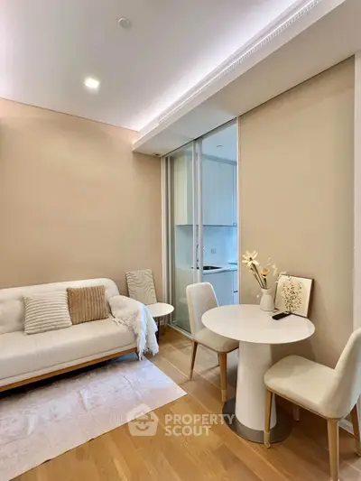 Modern living room with cozy seating and dining area, featuring elegant decor and natural lighting.