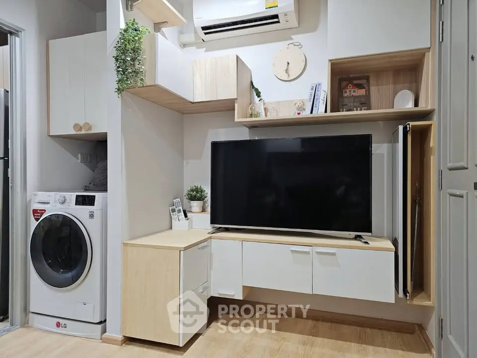 Modern living room with sleek TV unit and washing machine, showcasing efficient use of space.
