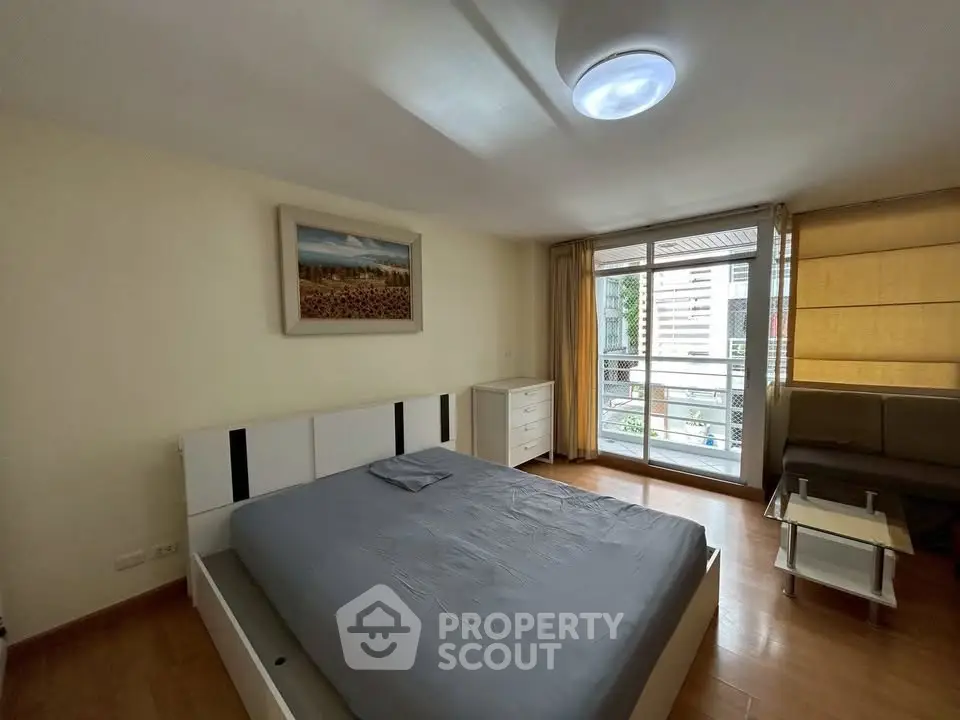 Spacious bedroom with modern decor and balcony access in urban apartment.