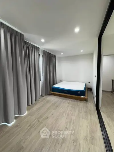 Spacious bedroom with modern decor and large windows for natural light.