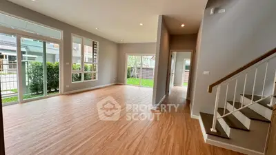 Spacious modern living room with large windows and wooden flooring, perfect for natural light lovers.