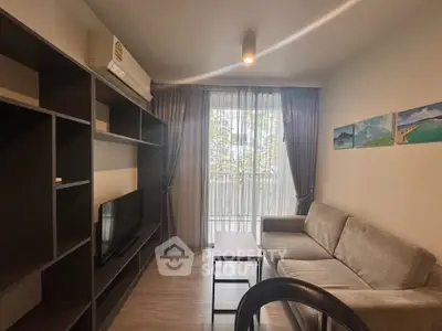Cozy living room with modern sofa and entertainment unit, featuring large window with sheer curtains.