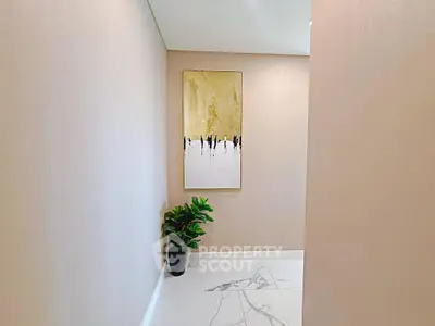 Elegant hallway with modern art and plant, featuring marble flooring.