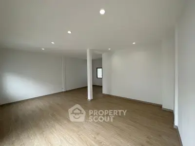 Spacious empty room with wooden flooring and recessed lighting, perfect for customization.
