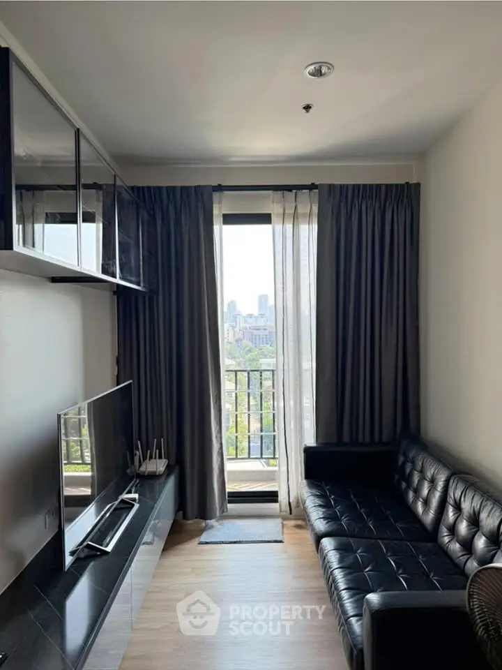 Modern living room with sleek black leather sofa and city view balcony, perfect for urban living.