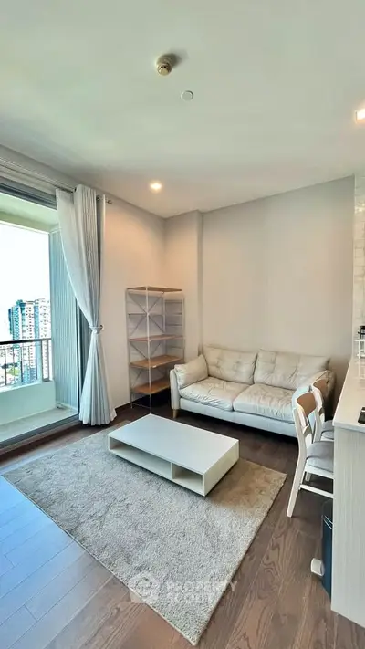 Modern living room with balcony view, featuring cozy sofa and stylish decor in a high-rise apartment.