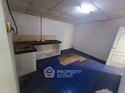Spacious kitchen with blue tiled floor and simple countertop, ready for renovation.