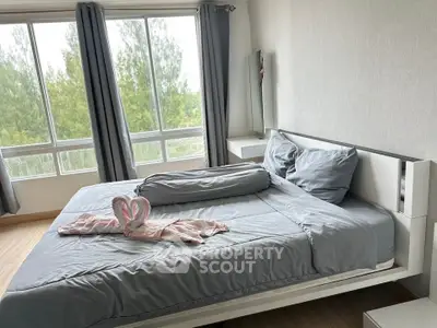 Spacious bedroom with large windows and elegant decor, offering a serene view of greenery.