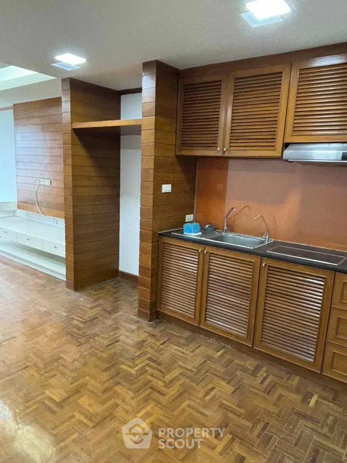 Charming kitchen with wooden cabinetry and parquet flooring, perfect for cozy home cooking.