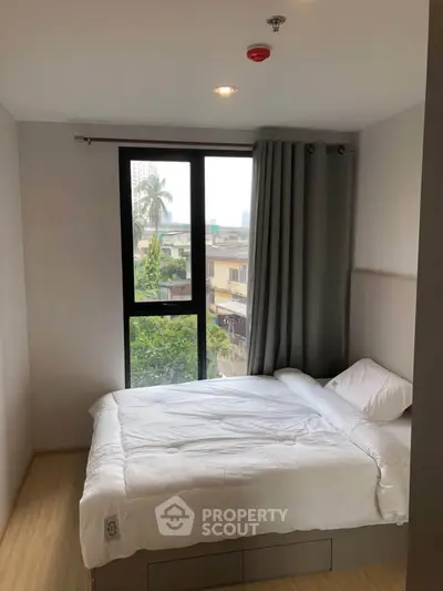 Cozy bedroom with large window and city view, featuring a comfortable bed and modern decor.