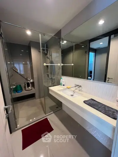 Modern bathroom with glass shower enclosure and sleek vanity in a contemporary home.