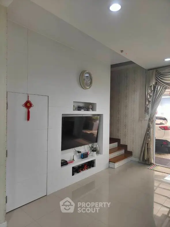 Modern living room with built-in TV and elegant staircase