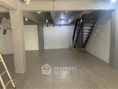 Spacious modern interior with sleek staircase and open layout, ideal for versatile living or office space.