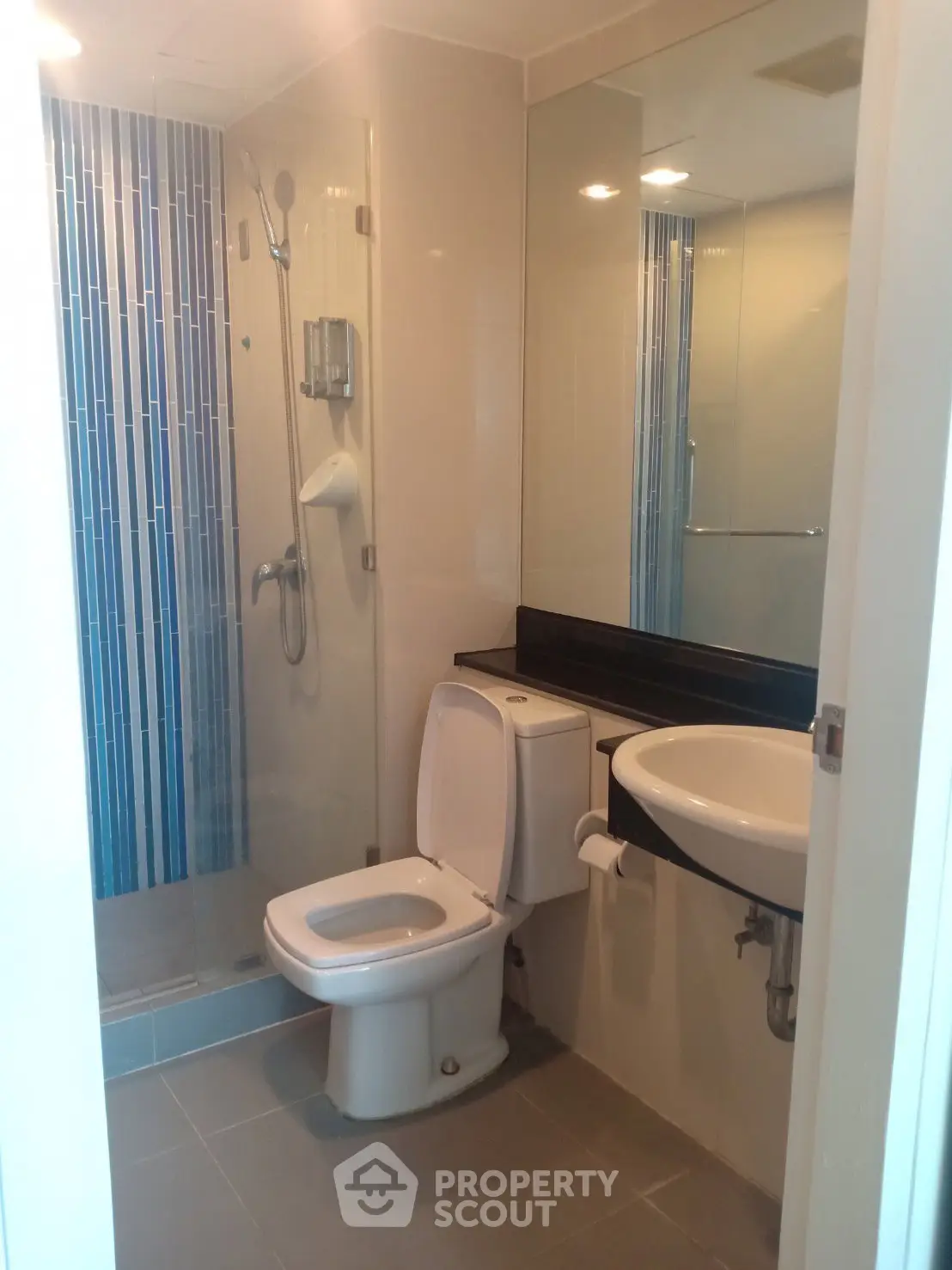 Modern bathroom with glass shower and sleek fixtures in contemporary apartment.