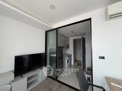 Modern apartment with open kitchen and living area featuring TV and washing machine.