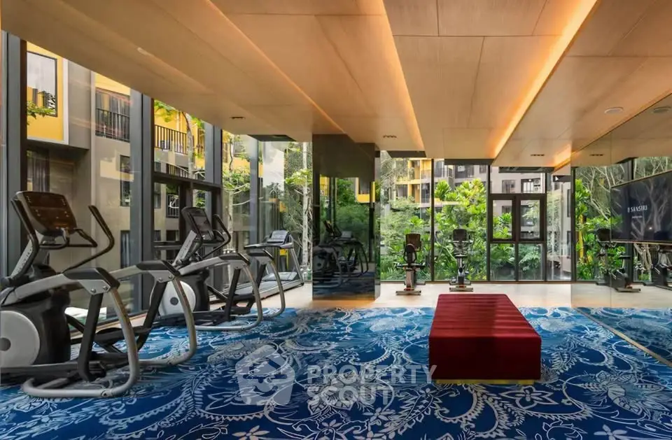 Luxurious gym with modern equipment and scenic garden view in upscale residential building.