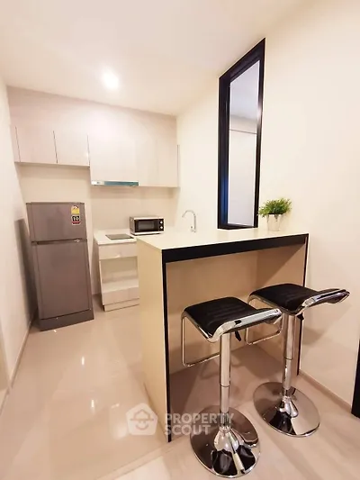 Modern compact kitchen with sleek bar stools and stainless steel appliances