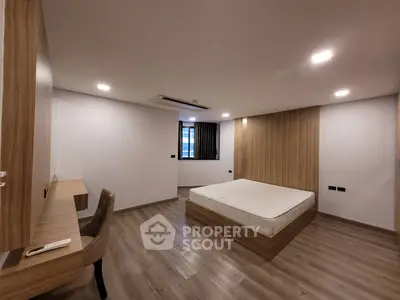 Spacious modern bedroom with wooden flooring and minimalist design
