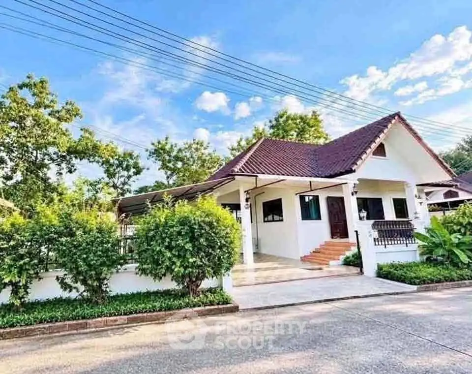 Charming single-story house with red roof and lush greenery in serene neighborhood.
