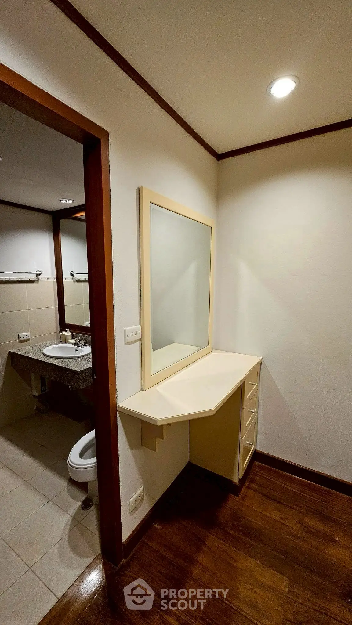 Cozy bathroom with wooden flooring and a corner vanity mirror, perfect for modern living.