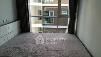 Cozy bedroom with large window offering a view of neighboring building.