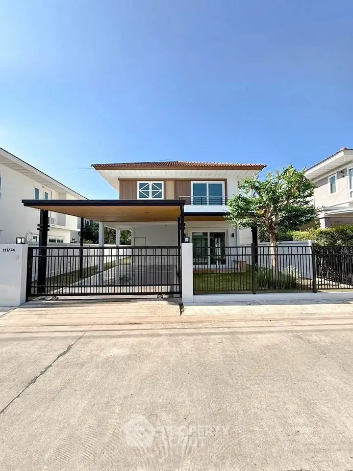 Modern two-story house with gated entrance and spacious driveway in a sunny neighborhood.