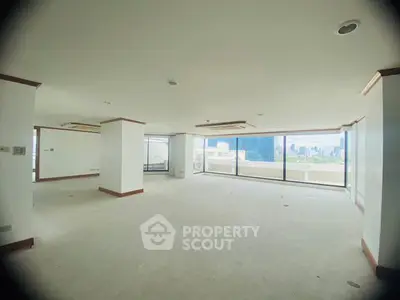 Spacious open-plan living area with panoramic city views and large windows.