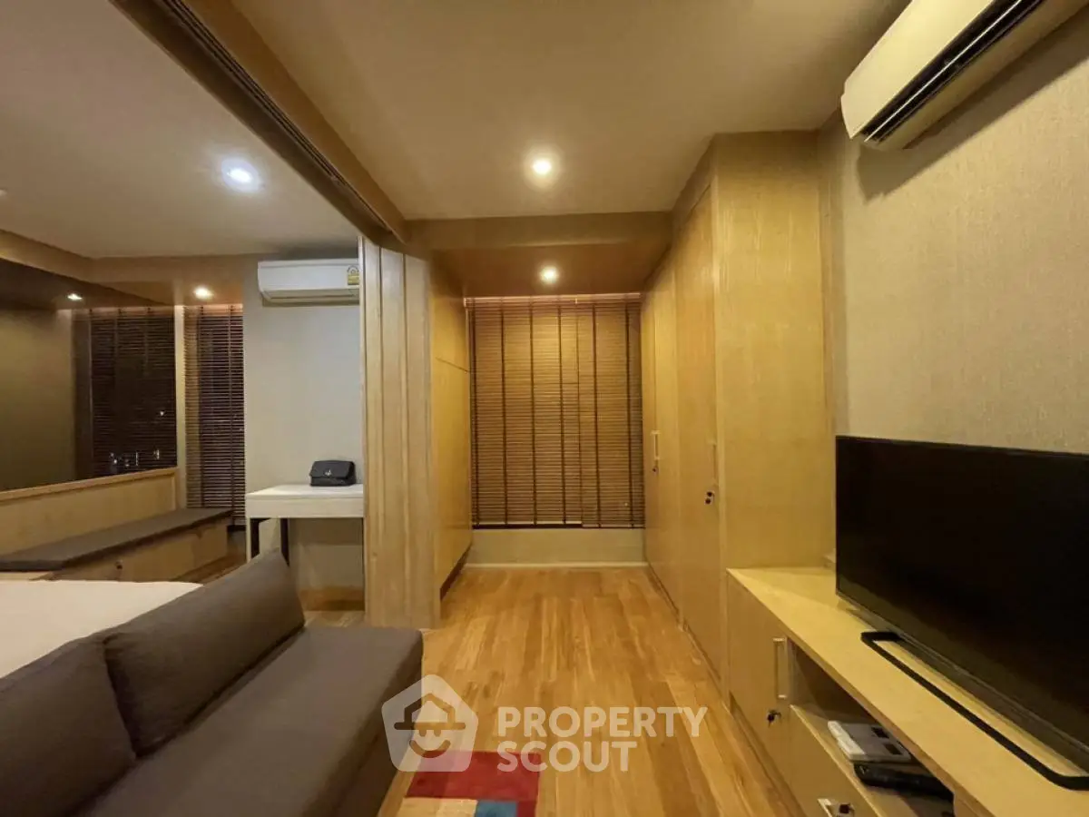 Modern bedroom with wooden flooring, air conditioning, and TV setup