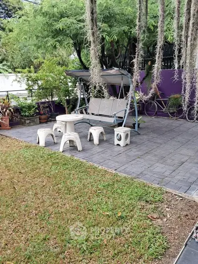 Charming garden patio with swing and seating area, perfect for relaxation and outdoor enjoyment.