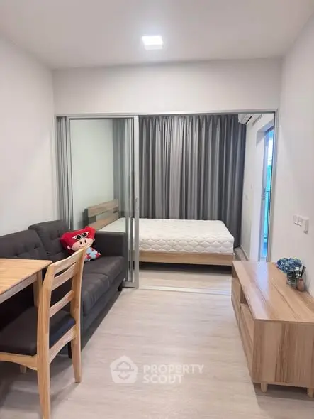 Modern studio apartment with cozy living area and bedroom separated by sliding glass doors.