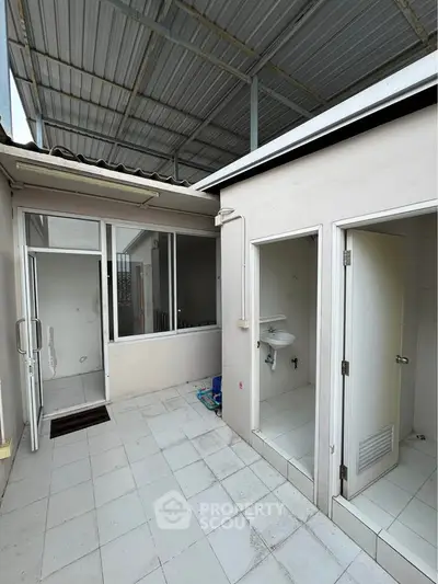 Spacious outdoor area with tiled flooring and covered roof, perfect for versatile use.