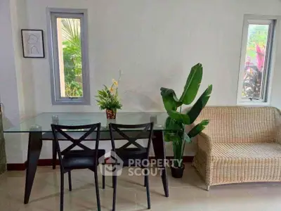 Charming interior with glass dining table, wicker sofa, and lush greenery for a cozy ambiance.