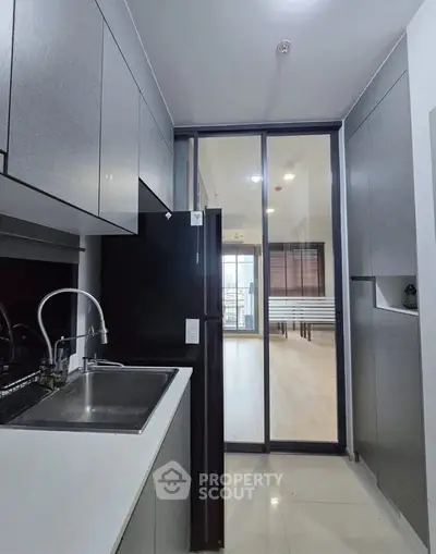 Modern kitchen with sleek cabinetry and sliding glass door leading to bright living area.
