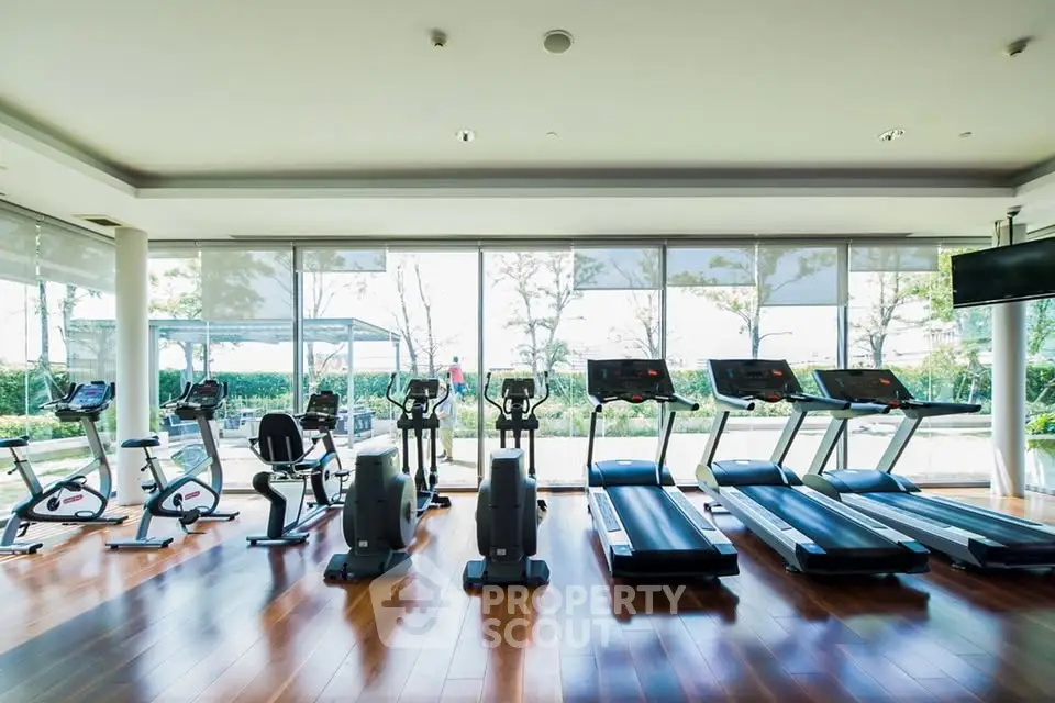 Spacious gym with modern equipment and large windows offering scenic views.
