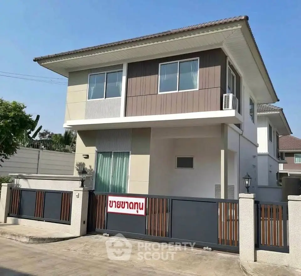 Modern two-story house with gated entrance and contemporary design.