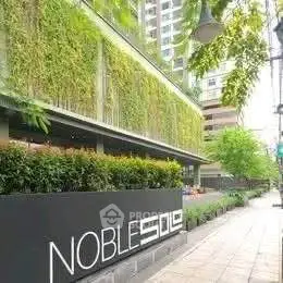 Modern building exterior with lush vertical garden and sleek signage on urban sidewalk.