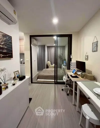 Modern studio apartment with glass partition, stylish decor, and compact workspace.