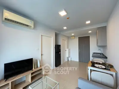 Modern living room with air conditioning and compact kitchen in open layout apartment.