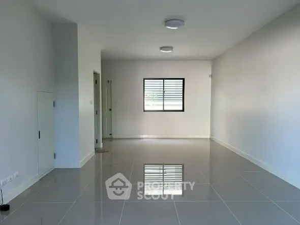 Spacious empty living room with glossy tiled floor and modern lighting.