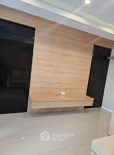 Modern minimalist living room with sleek wooden paneling and built-in shelving.