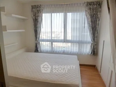 Bright bedroom with large window and elegant curtains, featuring a comfortable bed and wooden flooring.