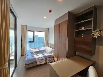 Modern bedroom with large windows and balcony access in a high-rise apartment.