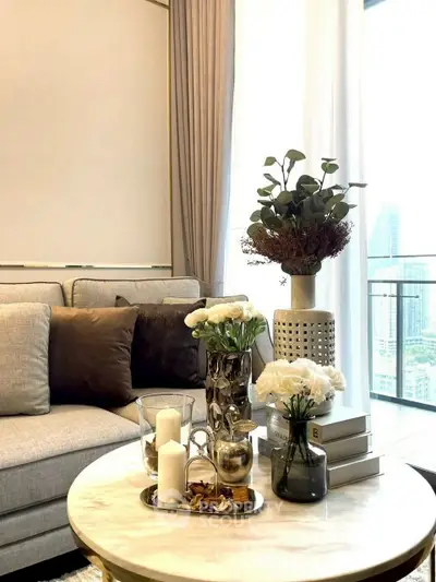 Elegant living room with modern decor and city view, featuring plush sofa and stylish coffee table.