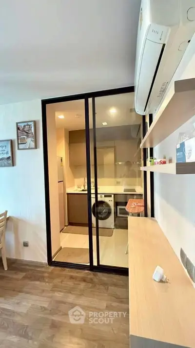 Modern apartment with open kitchen and laundry area, featuring sleek design and wooden flooring.